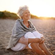 Seniorin sitzt am Strand